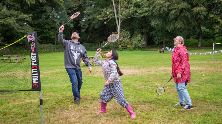 A family playing badminton in the garden.